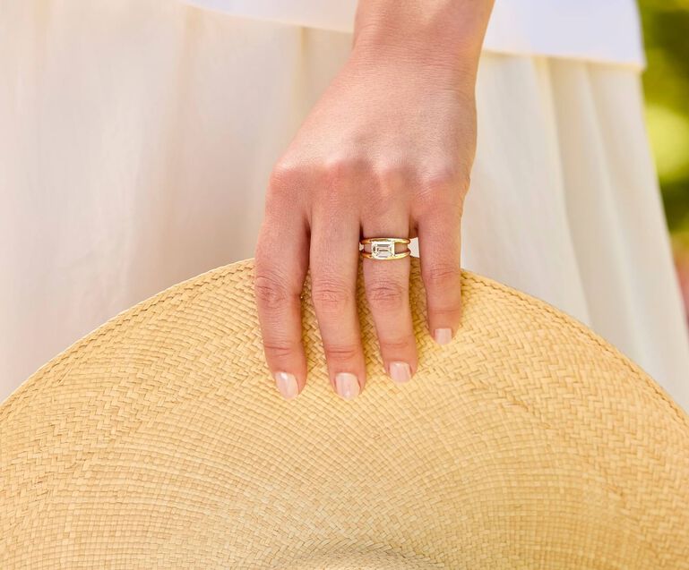Person wearing engagement ring while holding hat